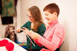 two woman knitting happily at a table